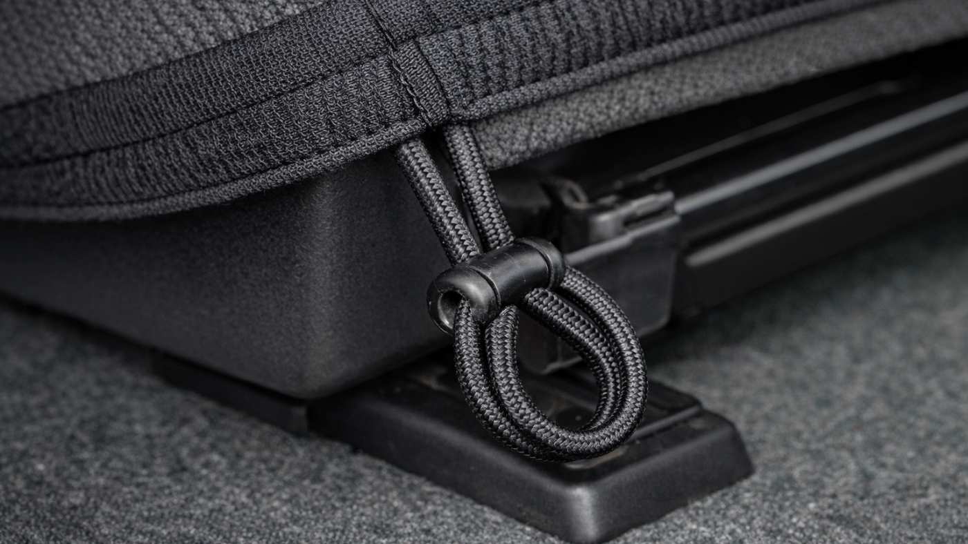 Loose seat cover strap and weak anchor loop under car seat showing poor tension and why sliding happens over time.