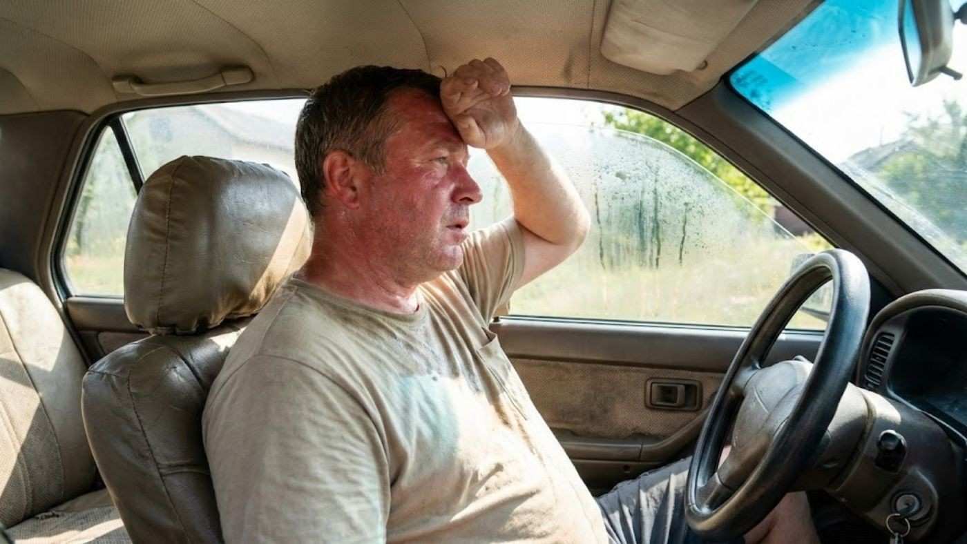 Sweaty driver in hot car showing need for ventilated seat covers that improve airflow and reduce sticky heat discomfort.