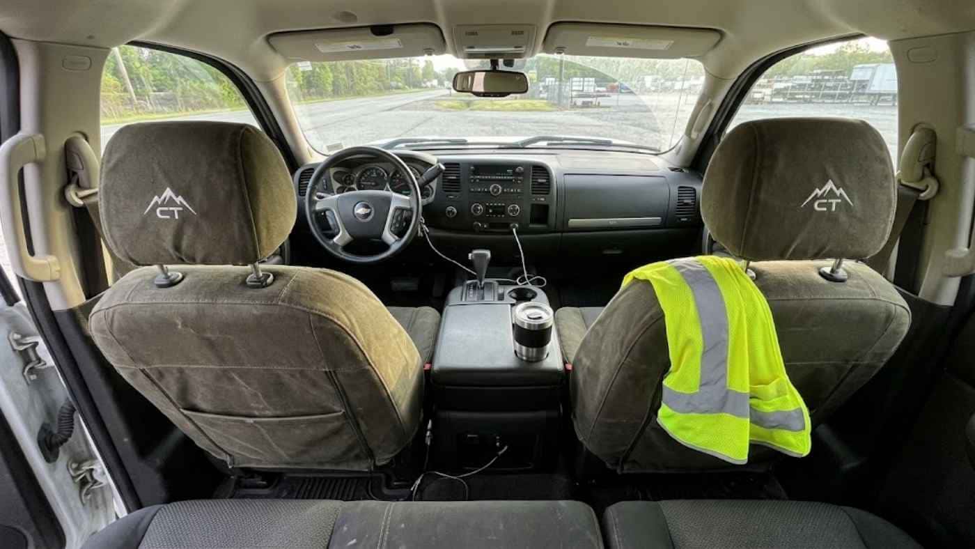 Canvas seat covers with embroidered headrest logos protecting a work truck interior built for durable daily commercial use.