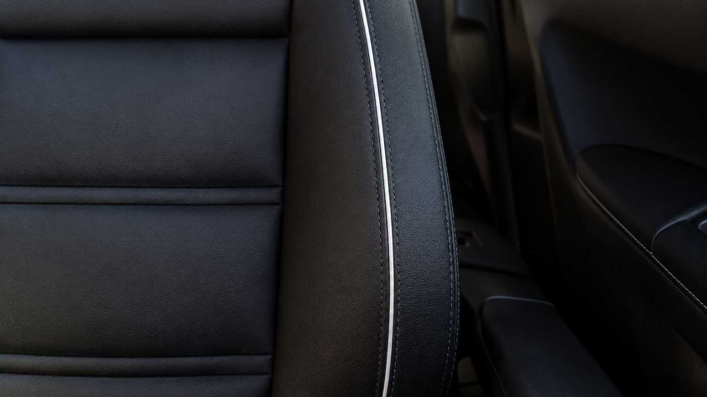 Black eco-leather seat cover with white contrast piping creating a factory-inspired premium interior finish.